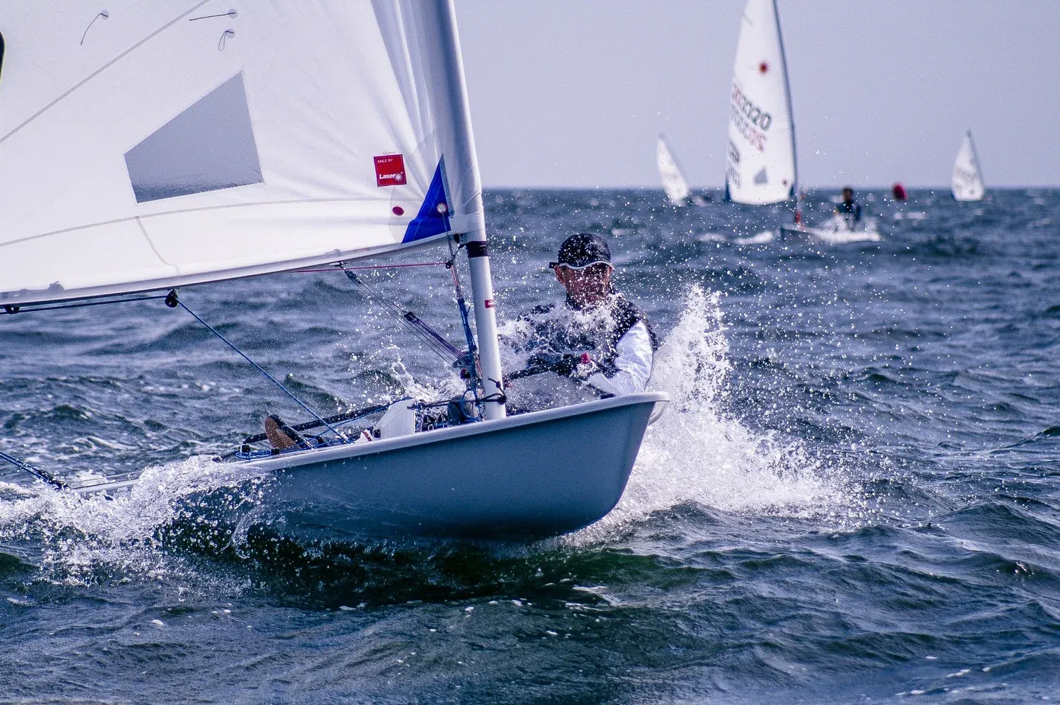 Sailor in a dinghy on open water, the sail full of wind